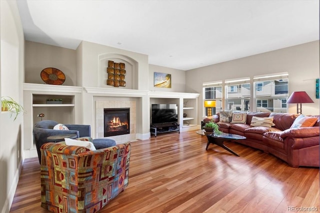 4236 Frederick Cir, Longmont, CO 80503 - living room featuring built in shelves, a tiled fireplace, and light wood-style flooring