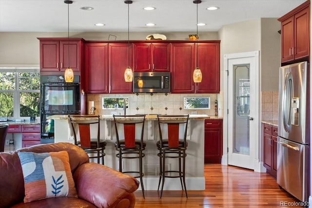 4236 Frederick Cir, Longmont, CO 80503 - kitchen with stainless steel appliances, reddish brown cabinets, wood finished floors, pendant lighting, and recessed lighting