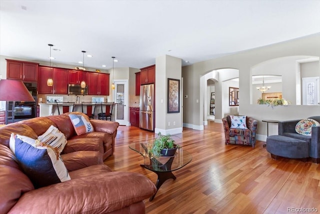 4236 Frederick Cir, Longmont, CO 80503 - living area featuring arched walkways, light wood-style flooring, a chandelier, and recessed lighting