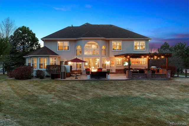 back of property at dusk featuring stucco siding, an outdoor hangout area, a lawn, and a patio area