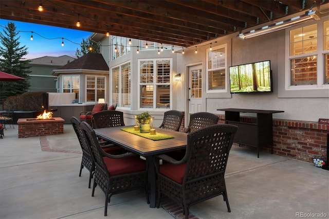 patio terrace at dusk with outdoor dining area and a fire pit