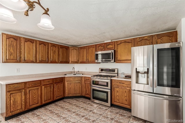 kitchen with stainless steel appliances, a textured ceiling, decorative light fixtures, light tile patterned flooring, and sink