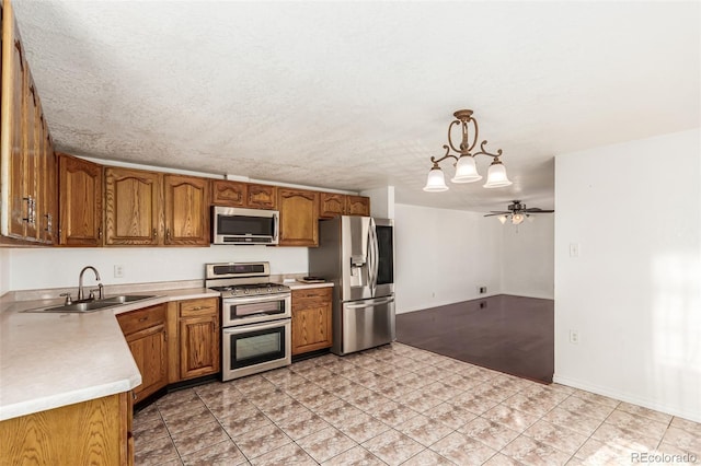 kitchen with a textured ceiling, decorative light fixtures, stainless steel appliances, ceiling fan with notable chandelier, and sink