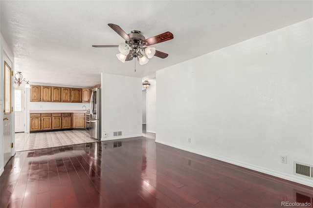 unfurnished living room with sink, light hardwood / wood-style flooring, and ceiling fan with notable chandelier