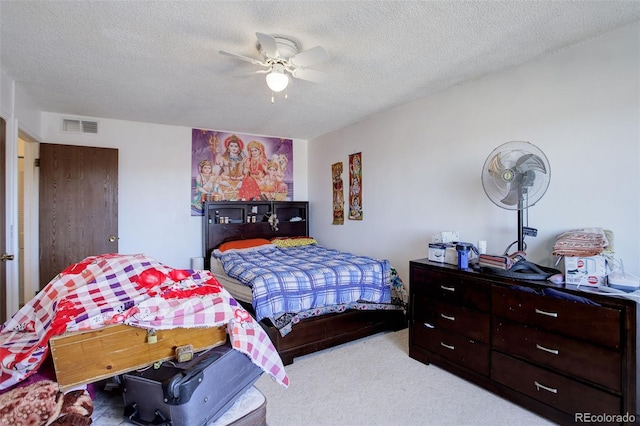 carpeted bedroom with ceiling fan and a textured ceiling