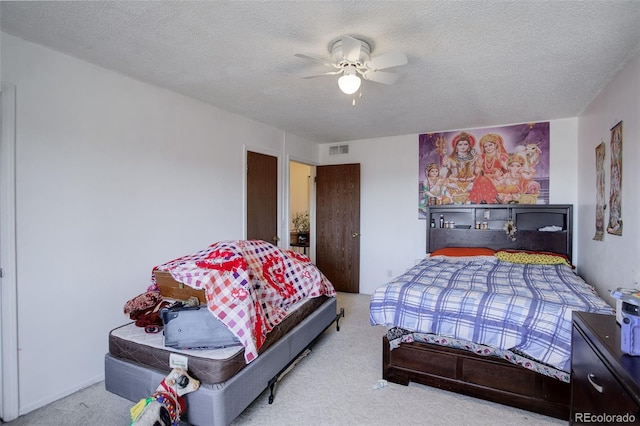 carpeted bedroom with ceiling fan and a textured ceiling