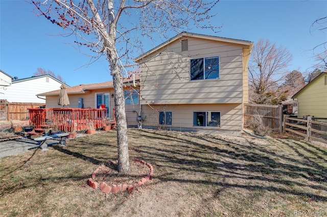 rear view of house featuring a wooden deck and a yard