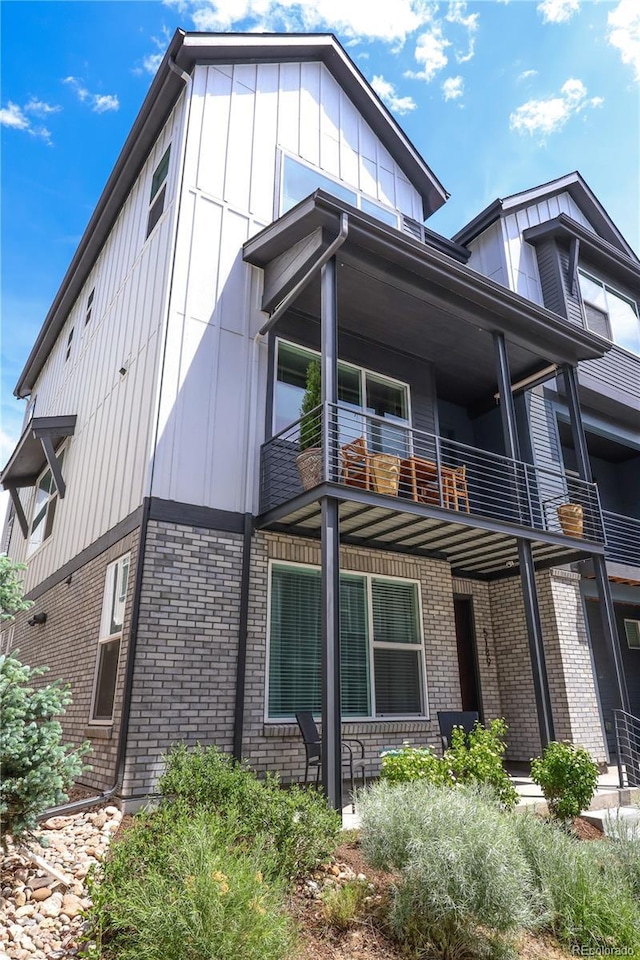 5189 Vivian St, Wheat Ridge, CO 80033 - view of side of home with a balcony, brick siding, and board and batten siding