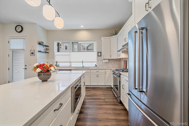 5189 Vivian St, Wheat Ridge, CO 80033 - kitchen featuring premium appliances, under cabinet range hood, backsplash, white cabinets, and recessed lighting