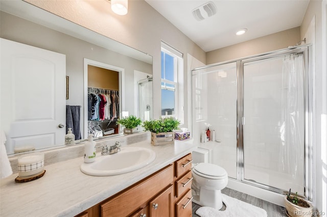 full bathroom featuring a stall shower, vanity, toilet, and a walk in closet