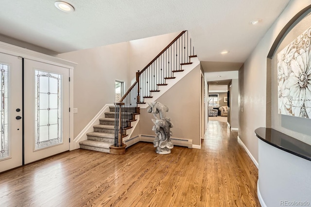 foyer with light wood-style floors, a wealth of natural light, stairway, and baseboards