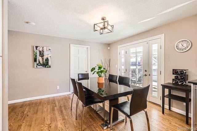 dining space featuring a notable chandelier, a textured ceiling, baseboards, and wood finished floors