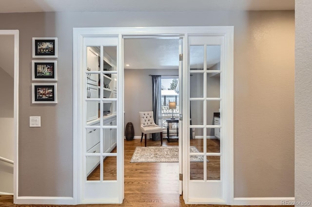 entryway featuring french doors, wood finished floors, and baseboards