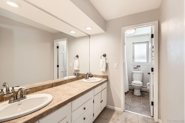 full bathroom with double vanity, a sink, and baseboards