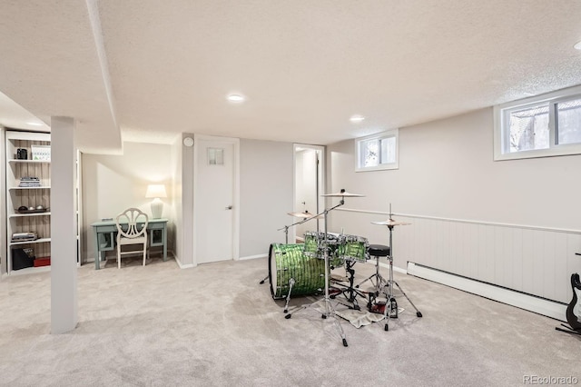 rec room with a wainscoted wall, a baseboard heating unit, a textured ceiling, and light colored carpet