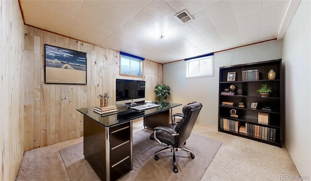 carpeted office space featuring visible vents and wood walls