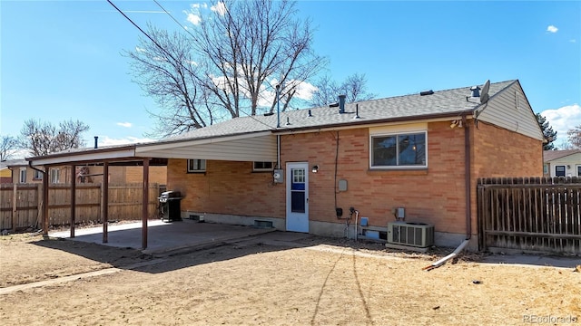 rear view of house with a patio, central AC unit, a fenced backyard, and brick siding