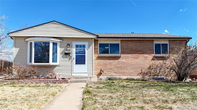 bungalow-style home featuring entry steps, brick siding, and a front yard