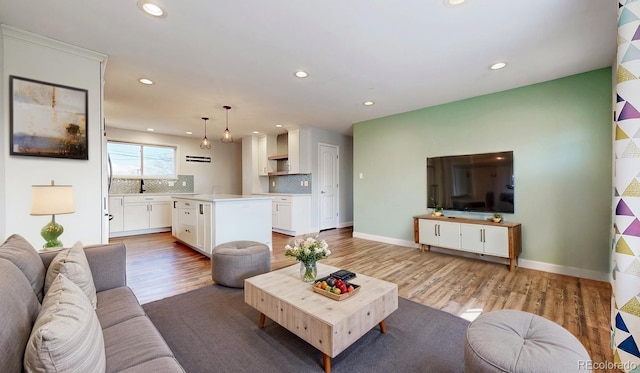 living area with baseboards, recessed lighting, and light wood-style flooring