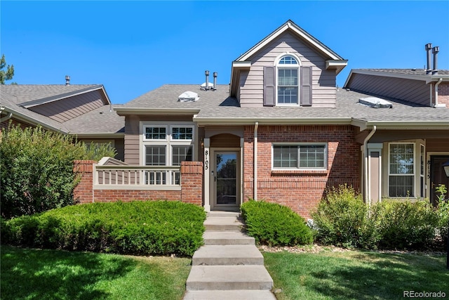 view of front of house with brick siding and roof with shingles