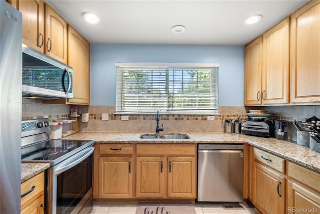 kitchen with visible vents, a sink, light stone counters, backsplash, and stainless steel appliances