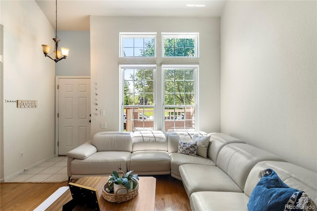 living area featuring a high ceiling, baseboards, light wood-type flooring, and a chandelier