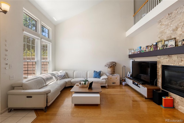 living room featuring a fireplace, high vaulted ceiling, and light wood-type flooring