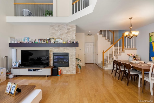 living area with baseboards, stairs, a fireplace, wood finished floors, and a notable chandelier