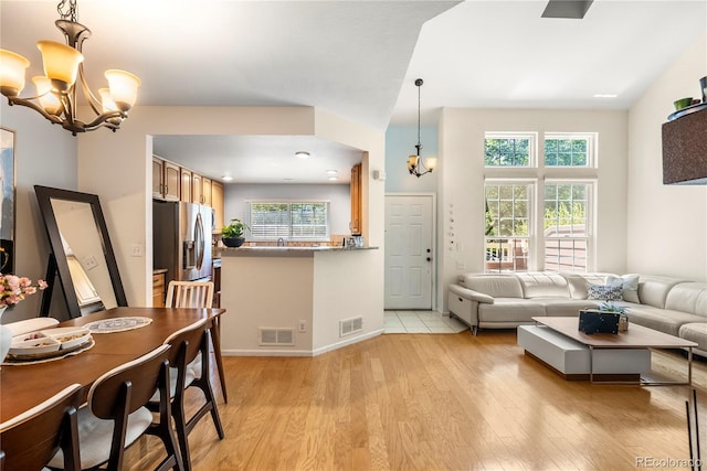 living room with plenty of natural light, a notable chandelier, visible vents, and light wood-type flooring