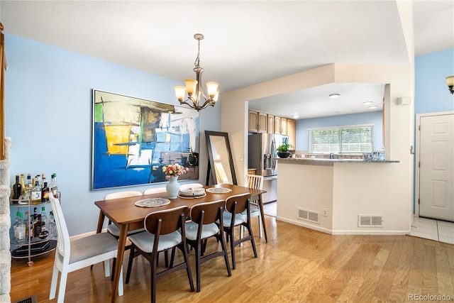 dining space featuring a notable chandelier, visible vents, and light wood finished floors