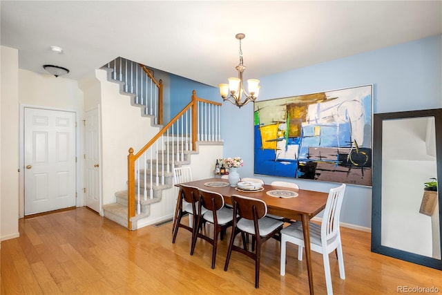 dining room with stairway, baseboards, a notable chandelier, and wood finished floors