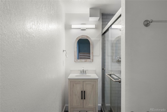 bathroom with vanity, a shower stall, and a textured wall