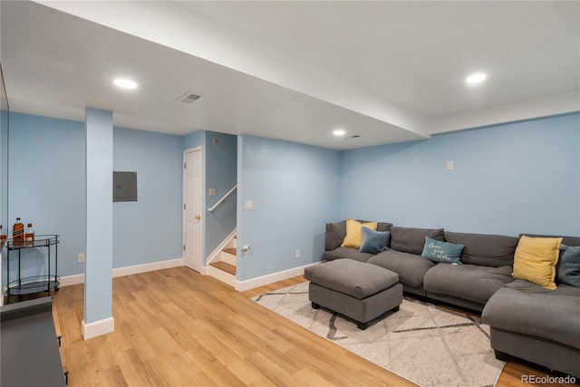 living area featuring visible vents, baseboards, stairs, electric panel, and light wood-style floors