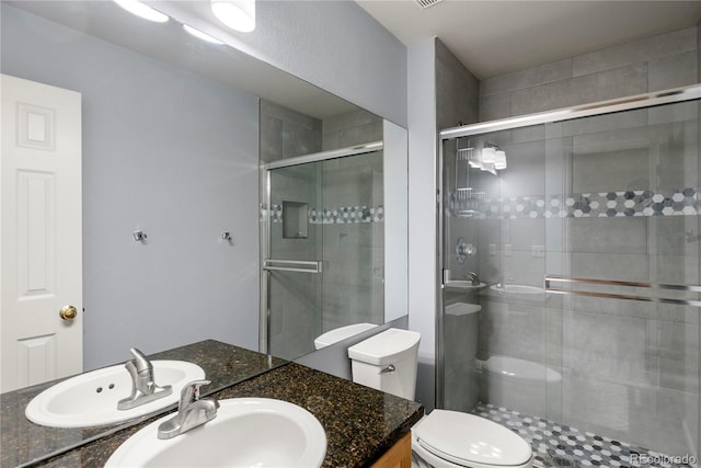 bathroom with vanity, a shower stall, and toilet