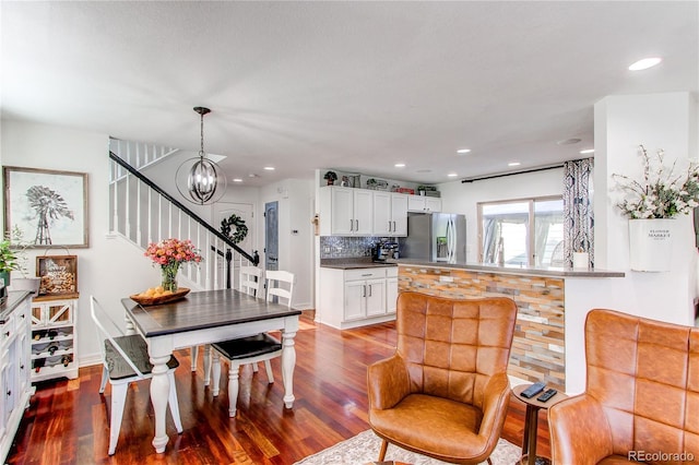 21418 E Stroll Ave, Parker, CO 80138 - kitchen with stainless steel fridge, wood finished floors, decorative backsplash, a chandelier, and white cabinets