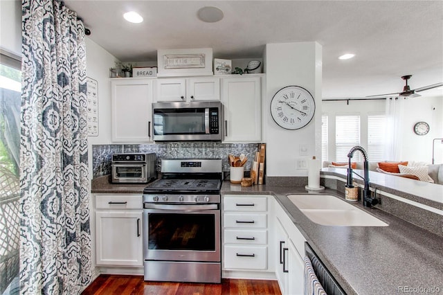 21418 E Stroll Ave, Parker, CO 80138 - kitchen with appliances with stainless steel finishes, a sink, dark countertops, dark wood-style floors, and white cabinetry