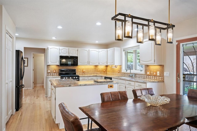 kitchen with black appliances, a sink, tasteful backsplash, a kitchen island, and white cabinets