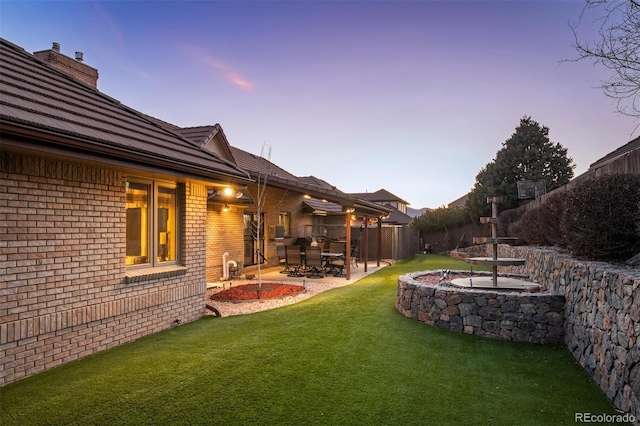 yard at dusk featuring a patio area and fence