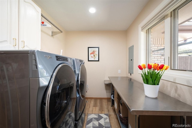 laundry room with electric panel, wood finished floors, washing machine and dryer, cabinet space, and baseboards