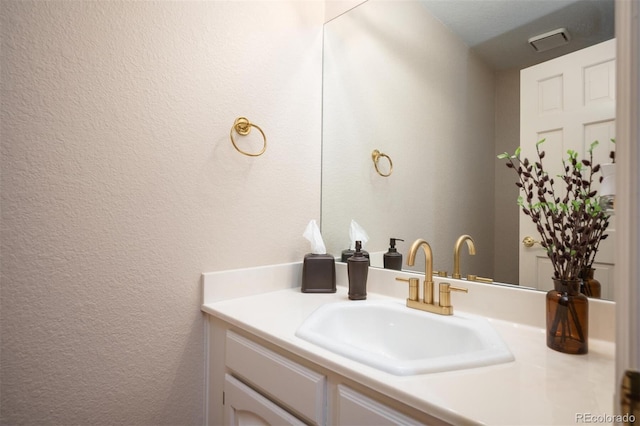 bathroom featuring vanity and a textured wall