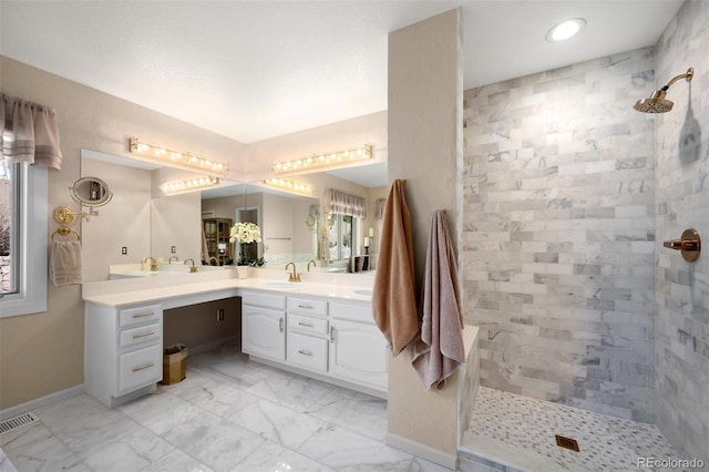 bathroom featuring visible vents, marble finish floor, tiled shower, baseboards, and vanity