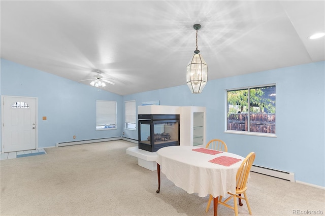 carpeted dining area featuring ceiling fan with notable chandelier, a baseboard heating unit, a multi sided fireplace, a baseboard radiator, and lofted ceiling