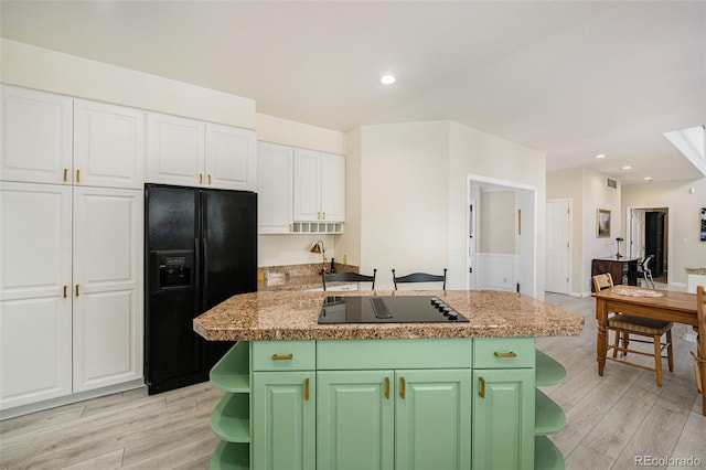 kitchen with black appliances, green cabinetry, white cabinets, and light hardwood / wood-style floors