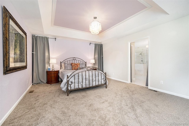 bedroom with a raised ceiling, an inviting chandelier, ensuite bathroom, and light colored carpet