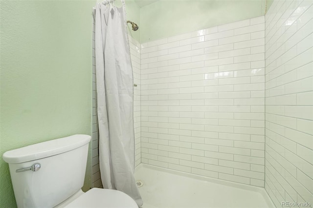 bathroom featuring a shower with shower curtain and toilet