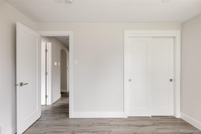 3540 Everett St, Wheat Ridge, CO 80033 - unfurnished bedroom featuring baseboards, a closet, light wood-style flooring, and arched walkways