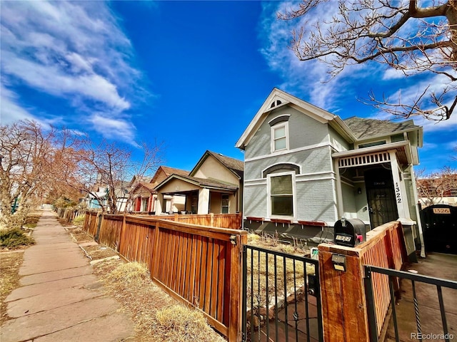 victorian home featuring a fenced front yard and brick siding