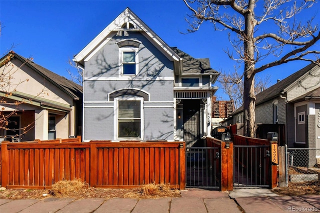 victorian home featuring a fenced front yard, a gate, and brick siding