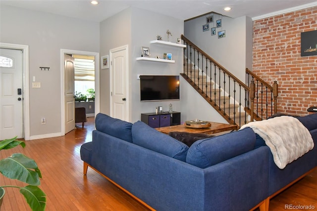 living room with recessed lighting, brick wall, baseboards, stairs, and wood-type flooring