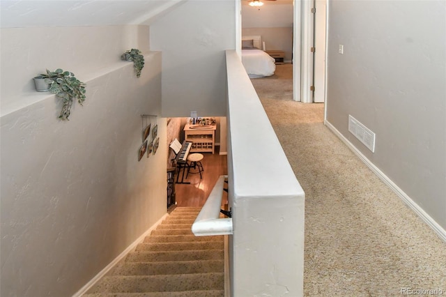 stairway with baseboards, visible vents, and carpet flooring